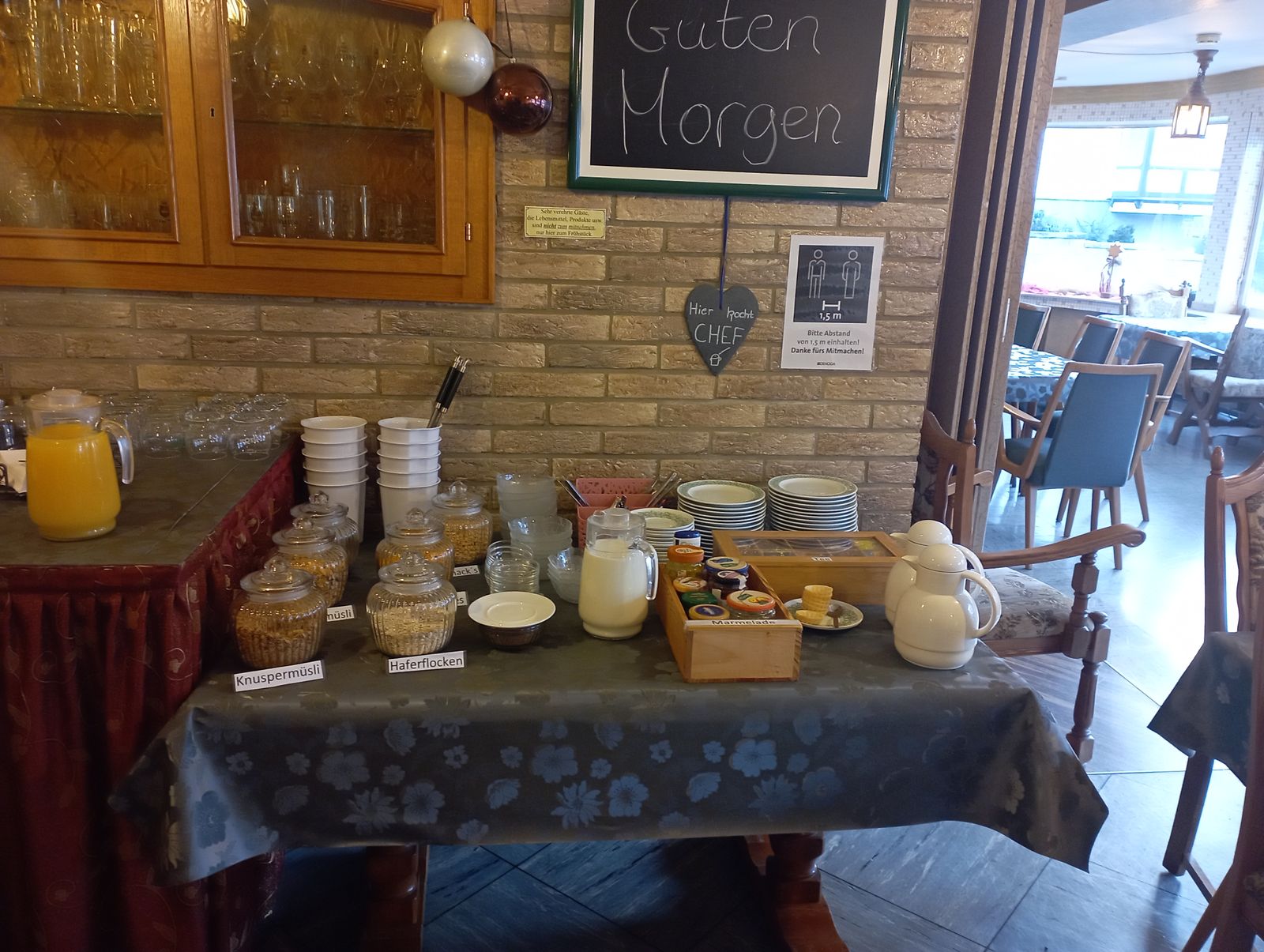 Tafel mit der Aufschrift Guten Morgen über dem Frühstücksbüfett, daneben ein Herz mit der Aufschrift Hier kocht Chef