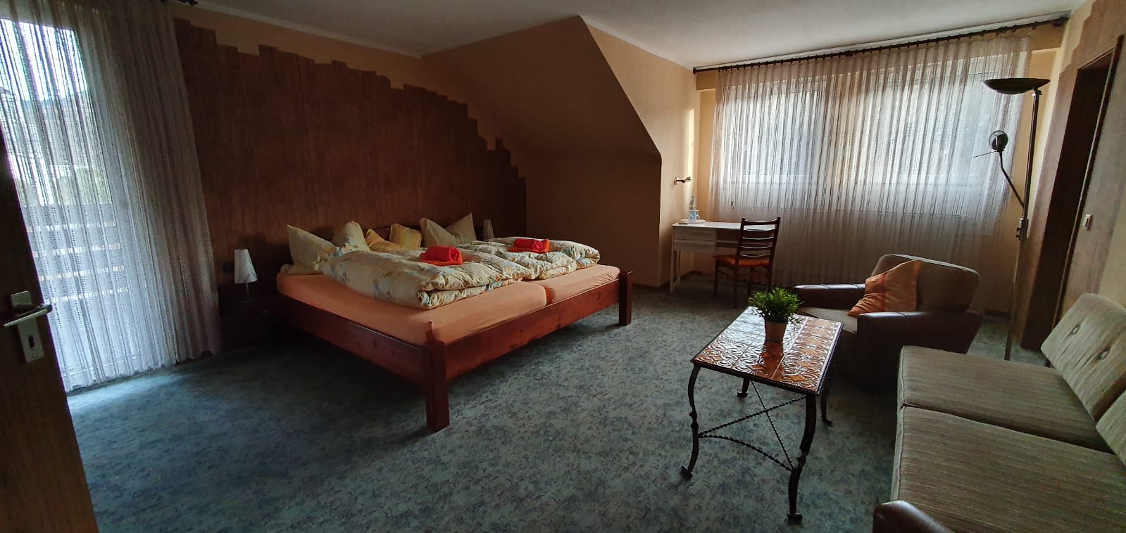 Großes Doppelzimmer mit Bett, Sitzecke, Schreibtisch und zwei Fenstern