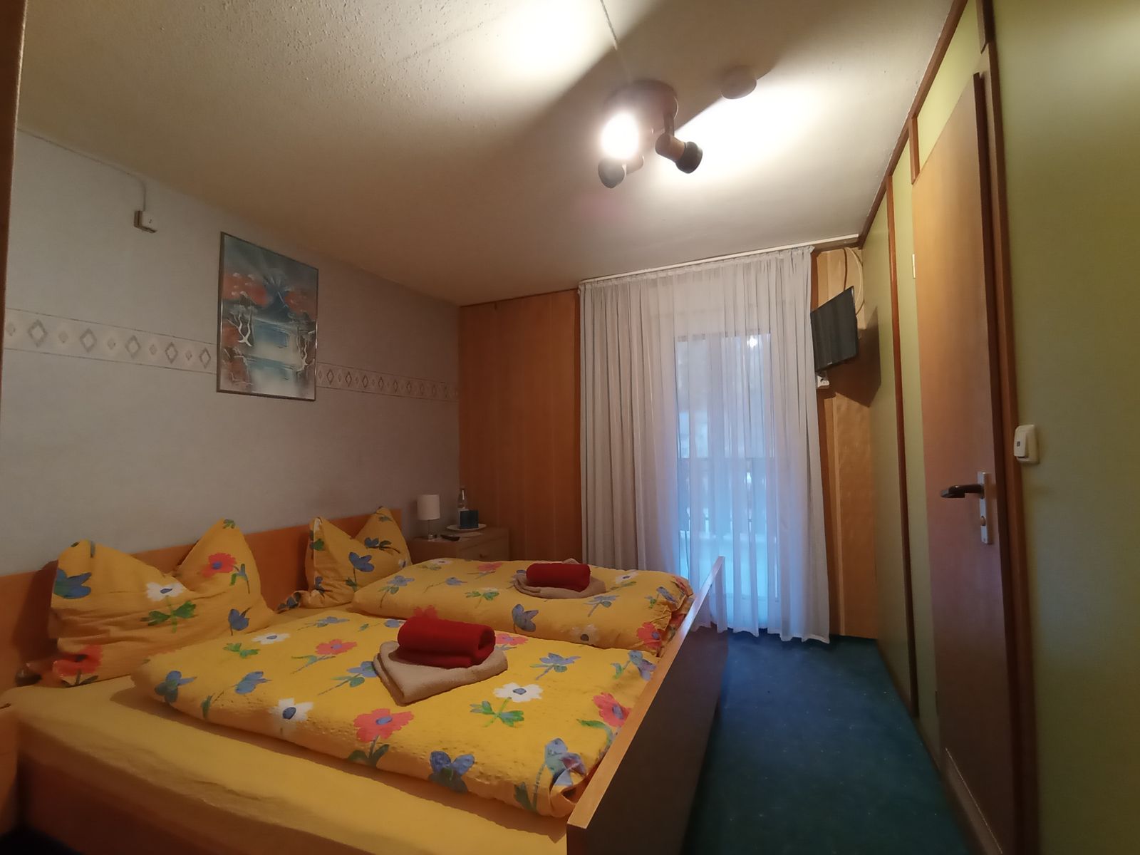 Kleines Doppelzimmer mit Doppelbett, Schrank und Fenster zum Balkon